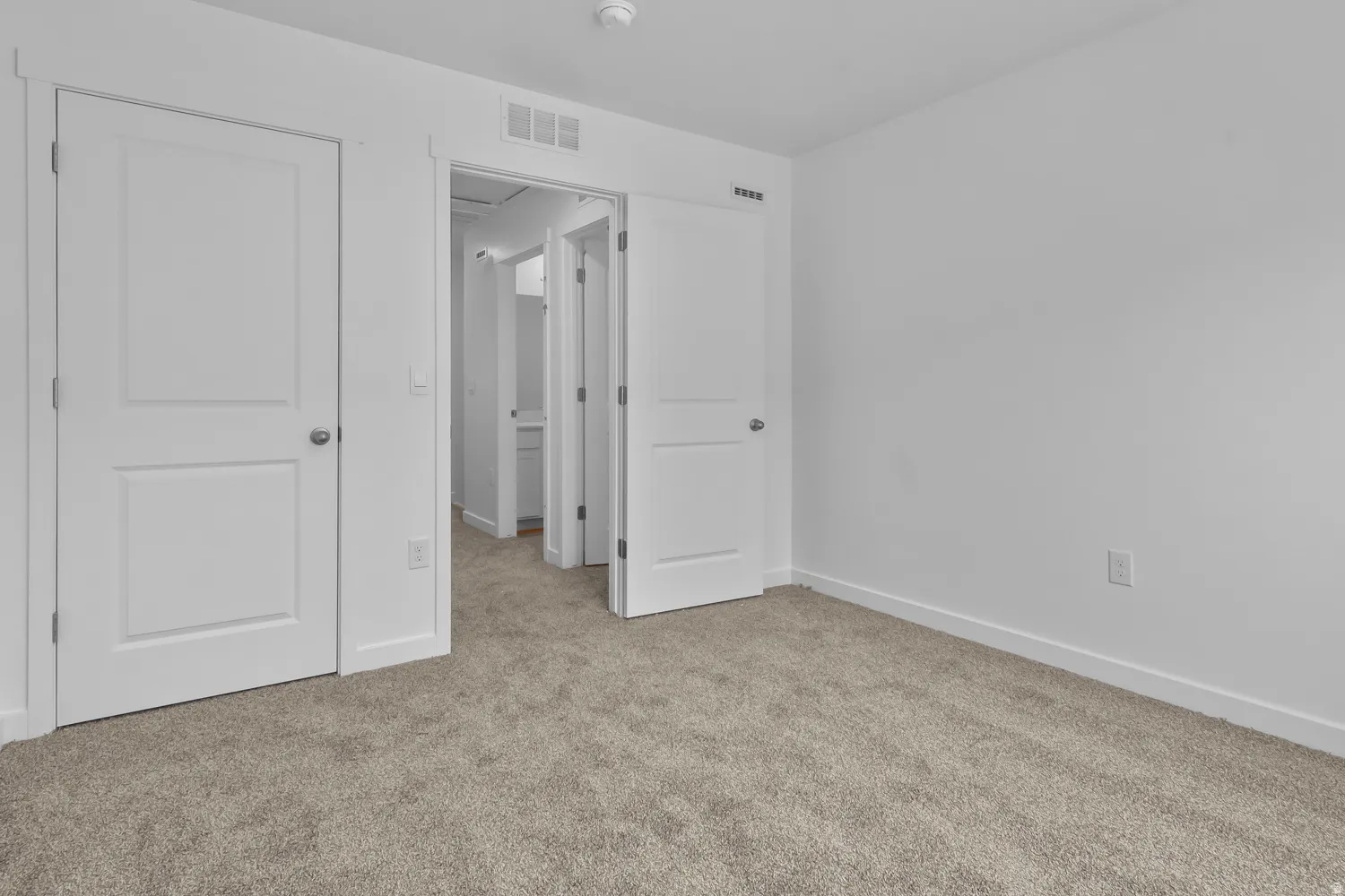 Neutral tone-on-tone carpeting and white walls define this space, featuring crisp white trim and solid core doors