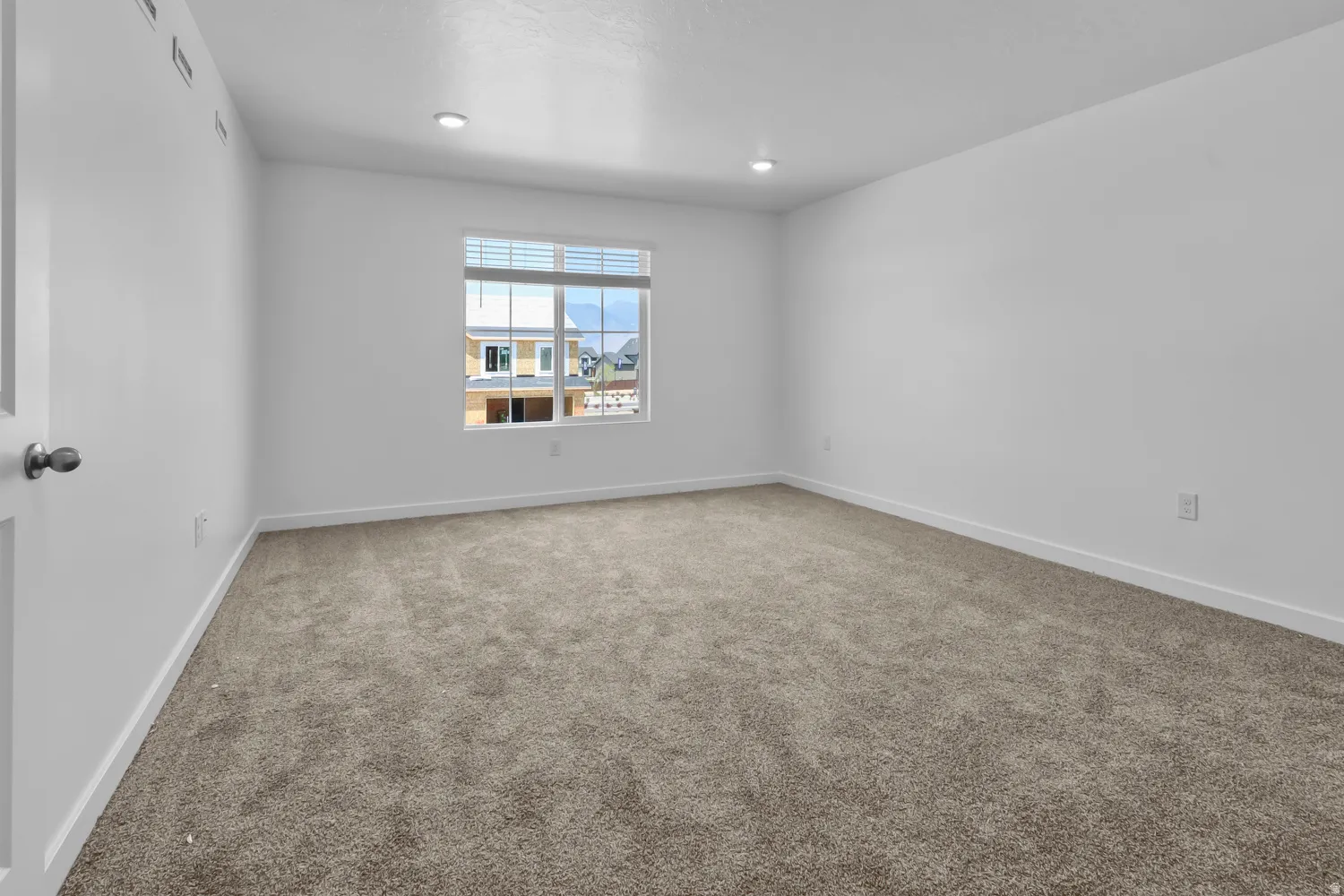 Carpeted room with recessed lighting and a window featuring white horizontal blinds