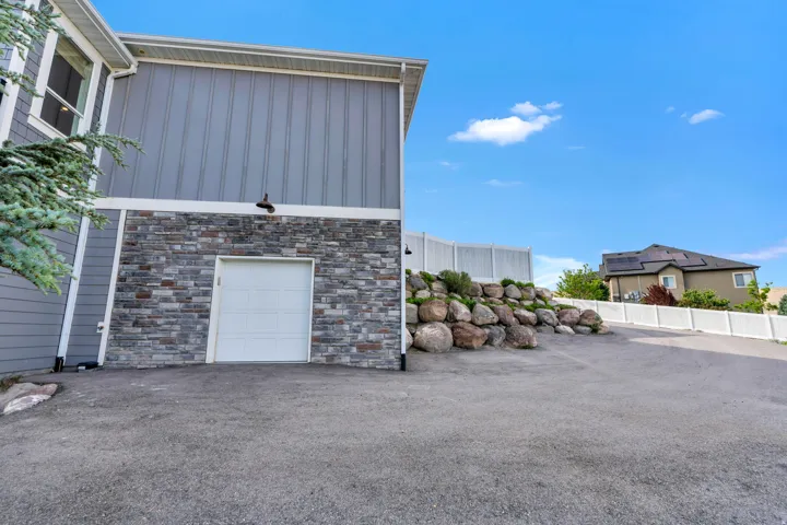Exterior featuring gray horizontal siding, vertical siding, stone veneer, and a white garage door