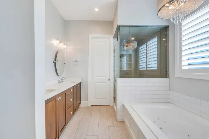 Contemporary bathroom featuring a double vanity with stone countertops, a jetted soaking tub, and a glass-enclosed shower