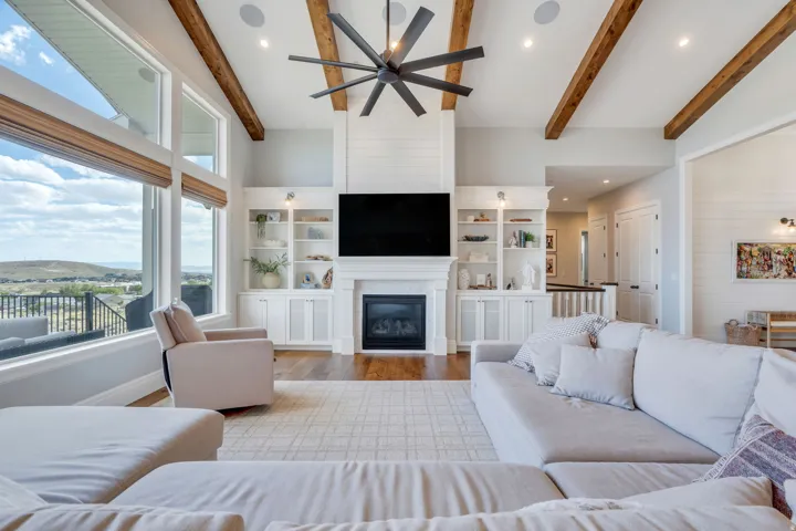 Spacious living area featuring exposed wood ceiling beams and a striking ceiling fan