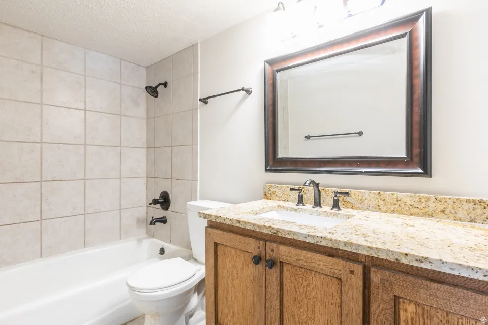 Bathroom featuring a wood vanity with a stone countertop, an undermount sink, and a framed mirror