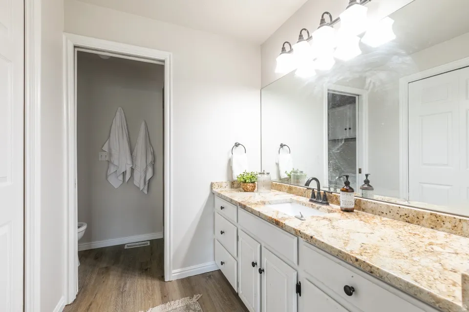 Spacious bathroom vanity featuring a light granite countertop, white cabinetry with dark hardware, a rectangular undermount sink, and a dark faucet