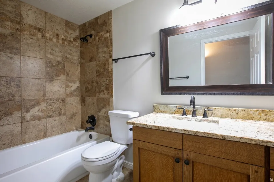 Bathroom featuring a light-toned vanity with a stone-finish countertop, undermount sink, and dark-toned hardware