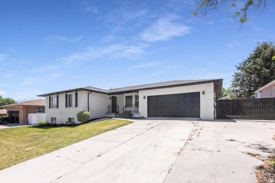Exterior featuring white painted brick, a black garage door, and a concrete driveway