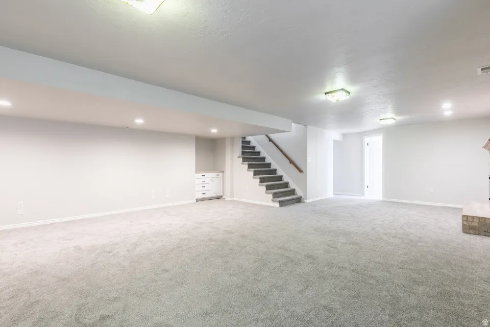 Spacious lower-level room featuring light gray carpeting and recessed lighting
