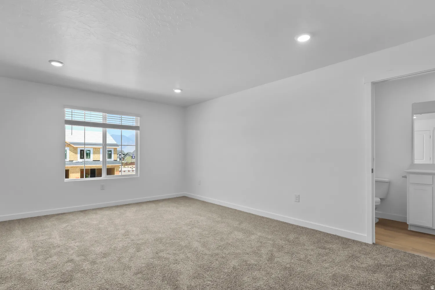 Spacious room featuring neutral carpeting and white walls