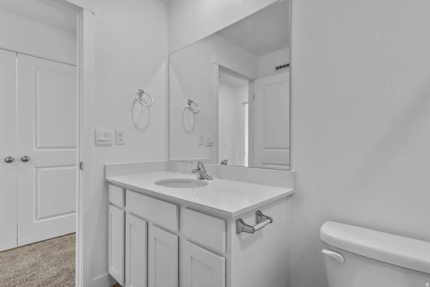 Bathroom vanity featuring a polished chrome faucet, under-mount sink, and white countertop