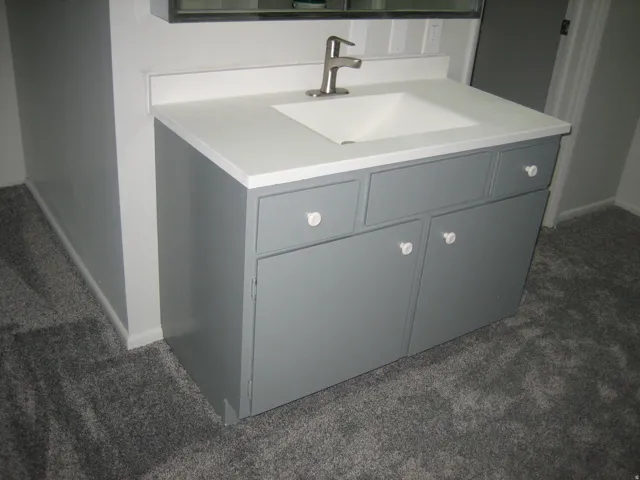 Grey vanity with white countertop, integrated sink, and brushed nickel faucet