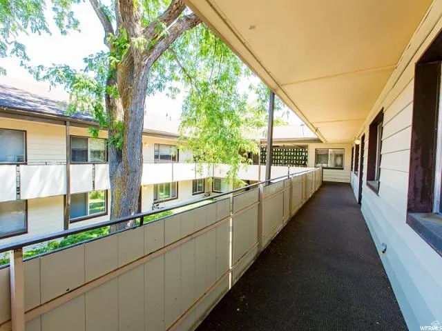 Covered exterior walkway featuring a protective railing and a carpeted surface