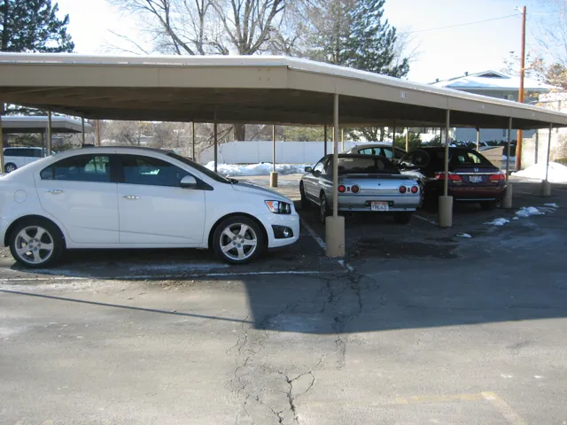 Covered parking structure featuring multiple bays, a light-colored metal roof, and supporting columns