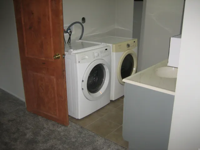 Utility area featuring a wood-panel door, tile flooring, and a vanity with an integrated sink and light-colored countertop