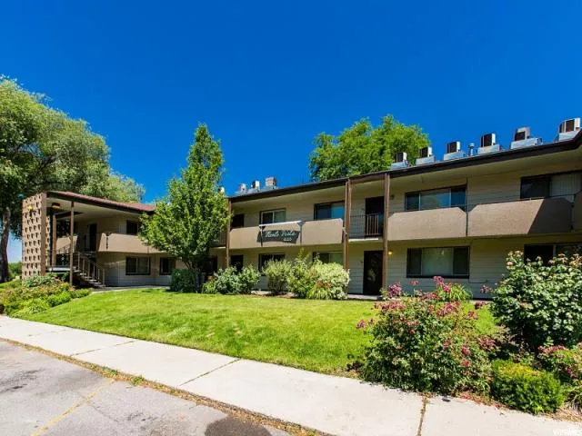 Multi-story residential building with light-toned siding and dark trim