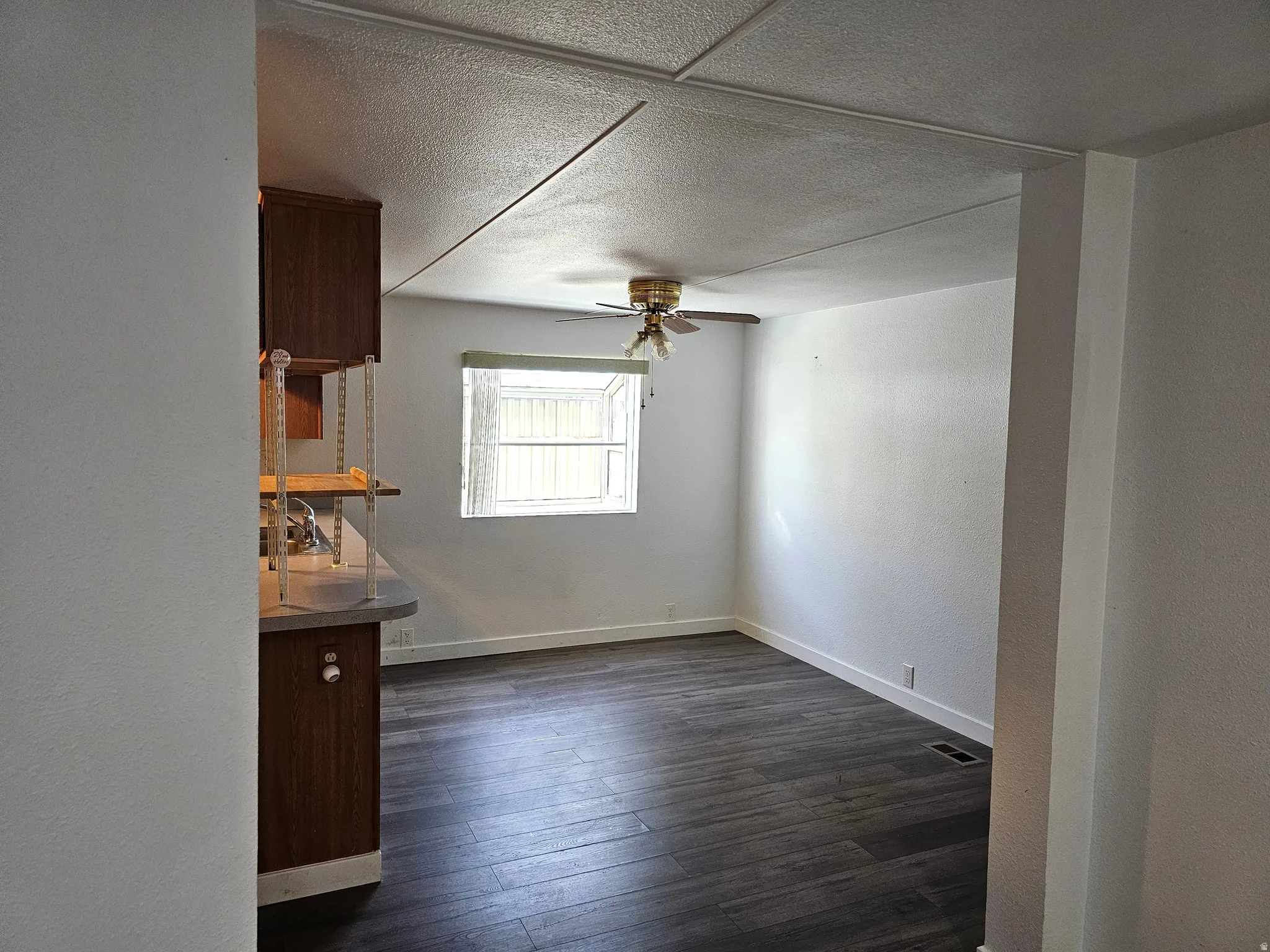 Interior space featuring wood-finish flooring, white walls, and a window with blinds