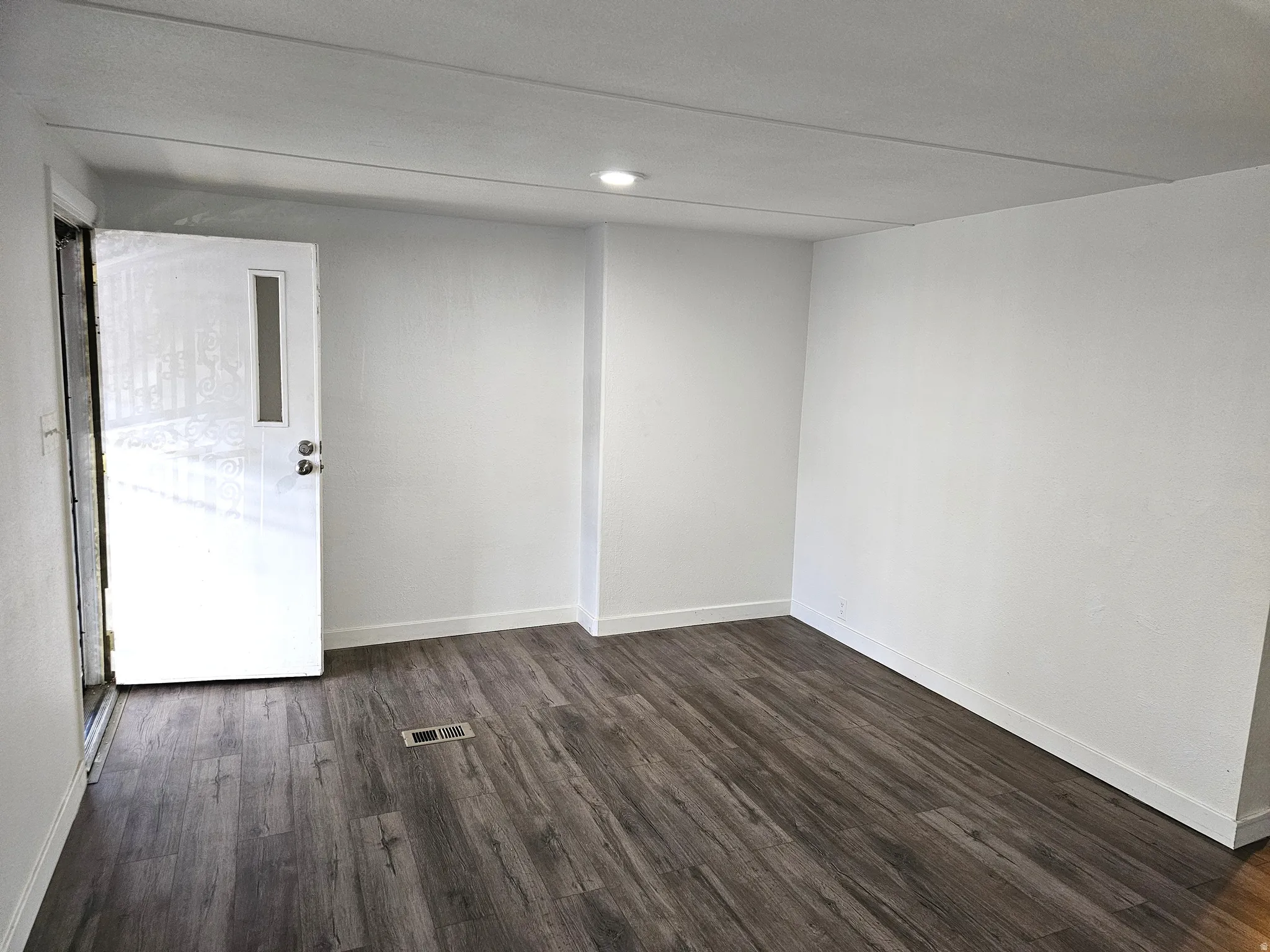 Entryway featuring wood-finish flooring, white baseboards, and a white door with a vertical window insert