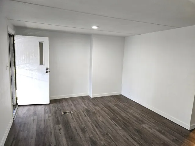 Entryway featuring wood-finish flooring, white baseboards, and a white door with a vertical window insert