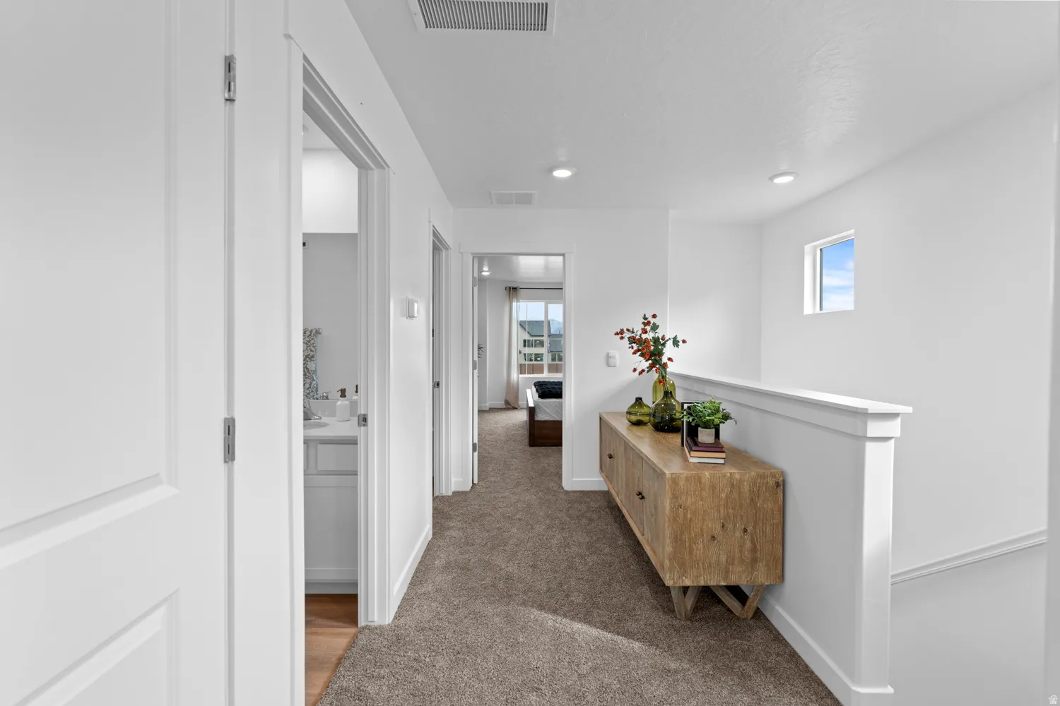 Carpeted hallway with white walls and recessed lighting