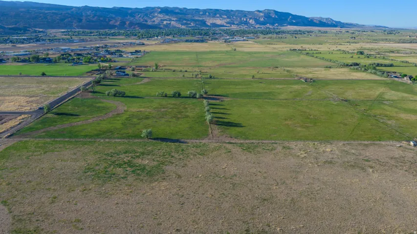 Expansive agricultural land featuring a mix of cultivated and uncultivated fields, with distant mountains forming a natural backdrop
