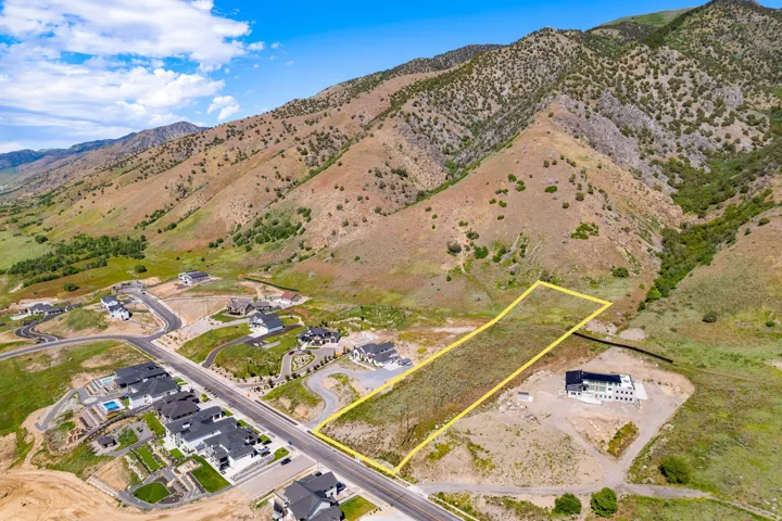 Expansive vacant land outlined in yellow, positioned at the base of a verdant mountain range