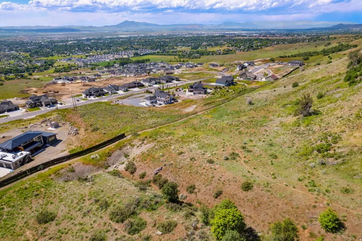 Expansive, undeveloped hillside property featuring natural vegetation and distant residential areas