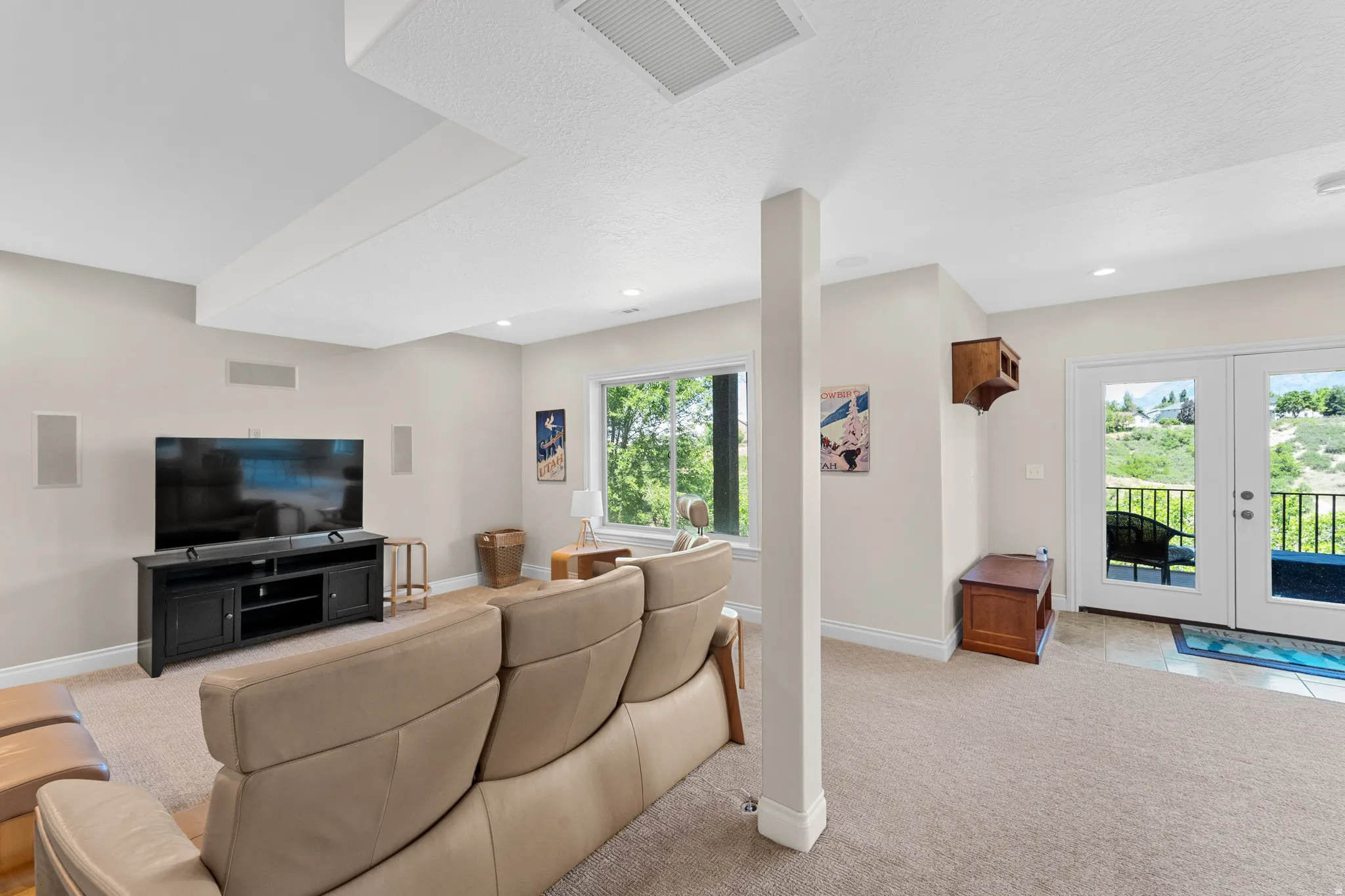 Spacious room featuring broadloom carpeting, a large window with exterior scenery, recessed ceiling lighting, and white French doors opening to an exterior railing