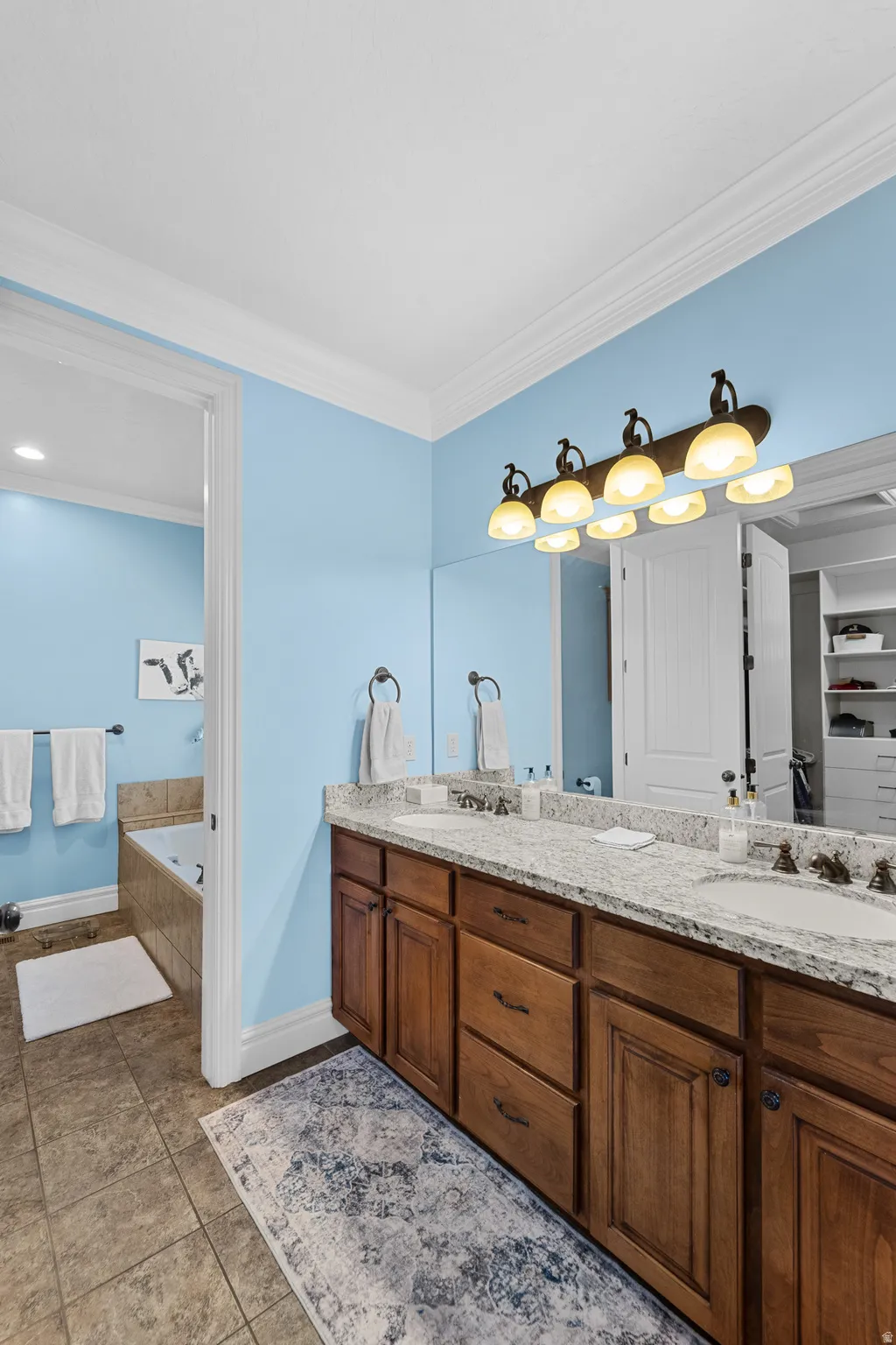 Dual vanity with granite countertop, integrated sinks, and bronze-finish lighting