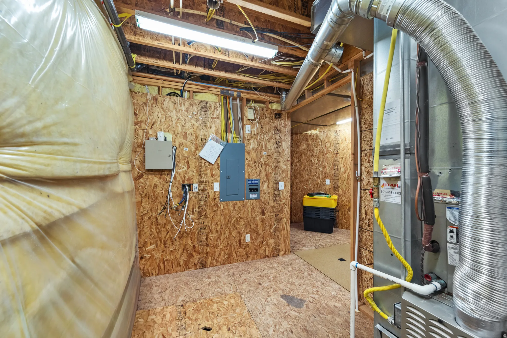Utility room with exposed ceiling joists and oriented strand board walls
