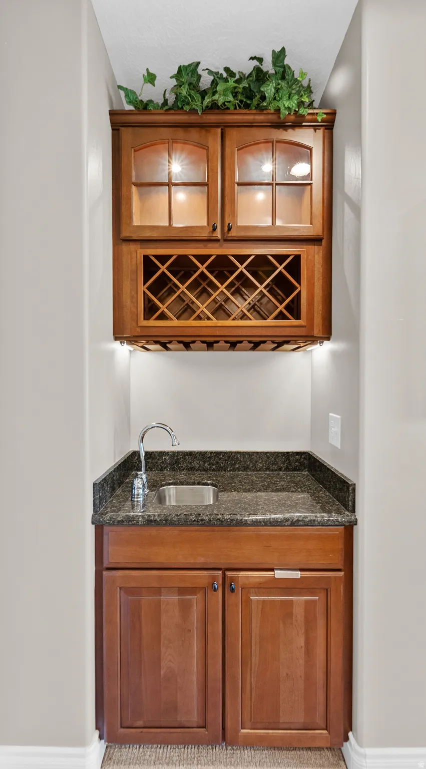 Dedicated wet bar featuring wood-finish cabinetry, a built-in wine rack, and under-cabinet stemware storage