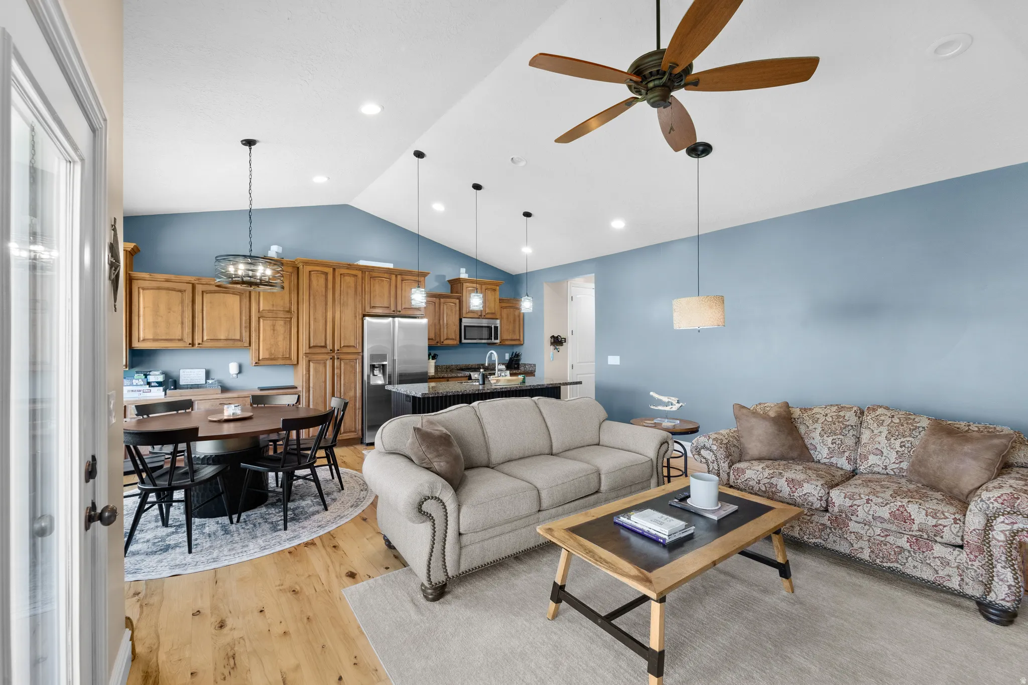 Open concept living area featuring vaulted ceilings, wood-finish flooring, and recessed lighting