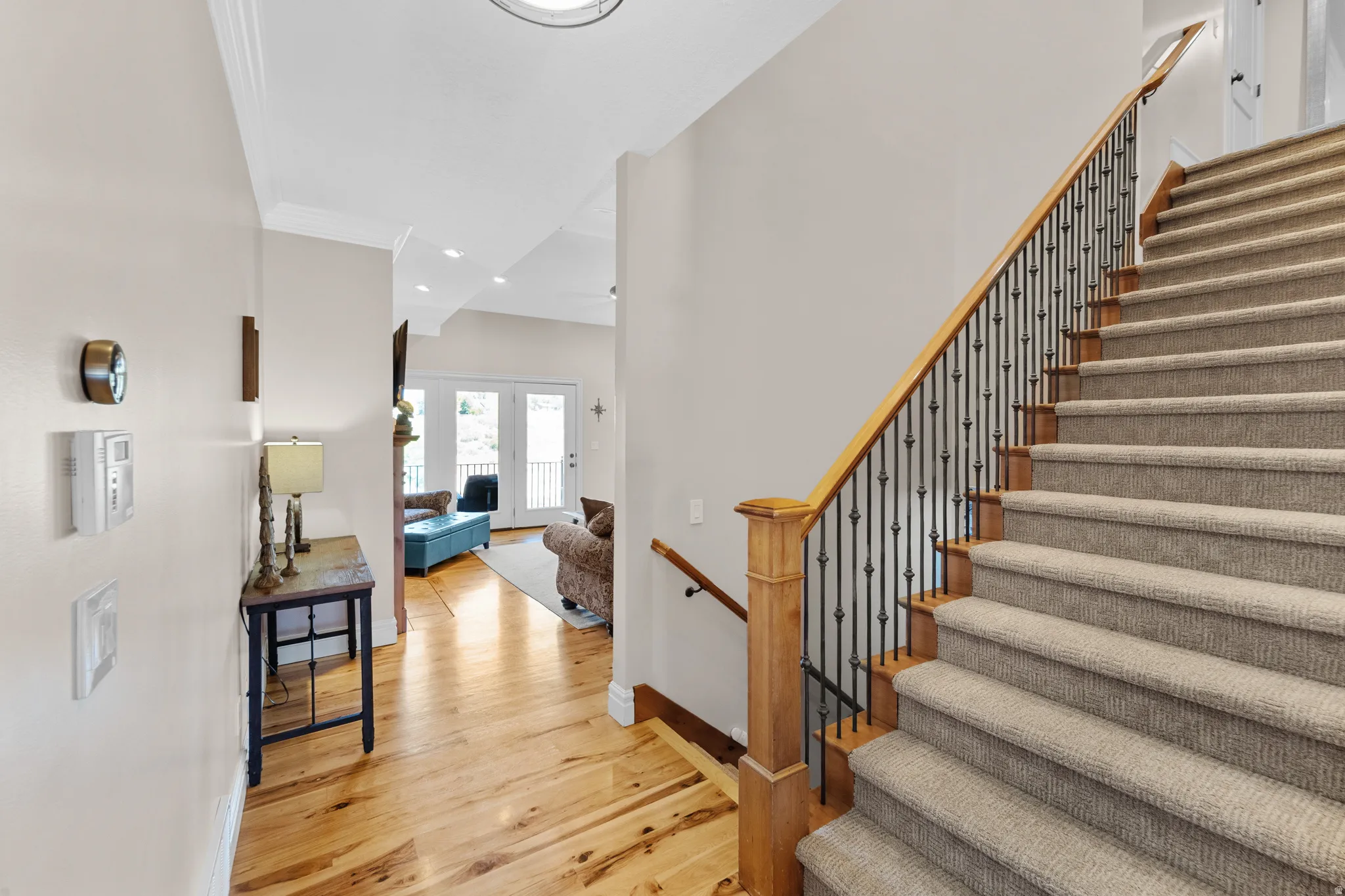 Hardwood flooring and carpeted staircase with wood newel posts and iron balusters