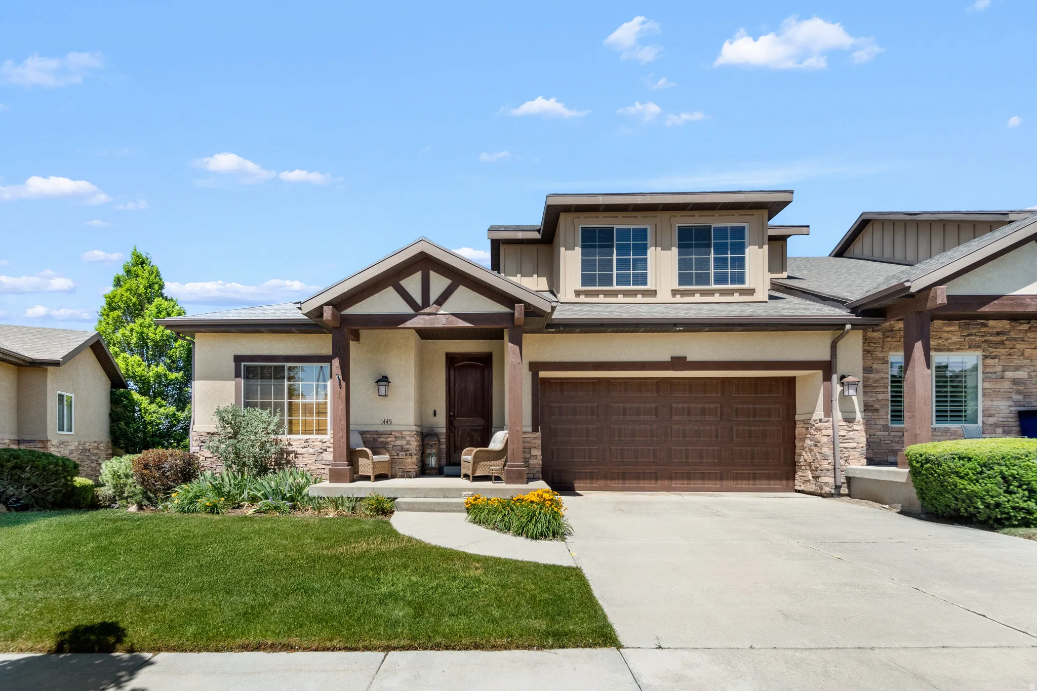 Craftsman-style facade featuring a covered entry, stone accents, and a wood-finish garage door