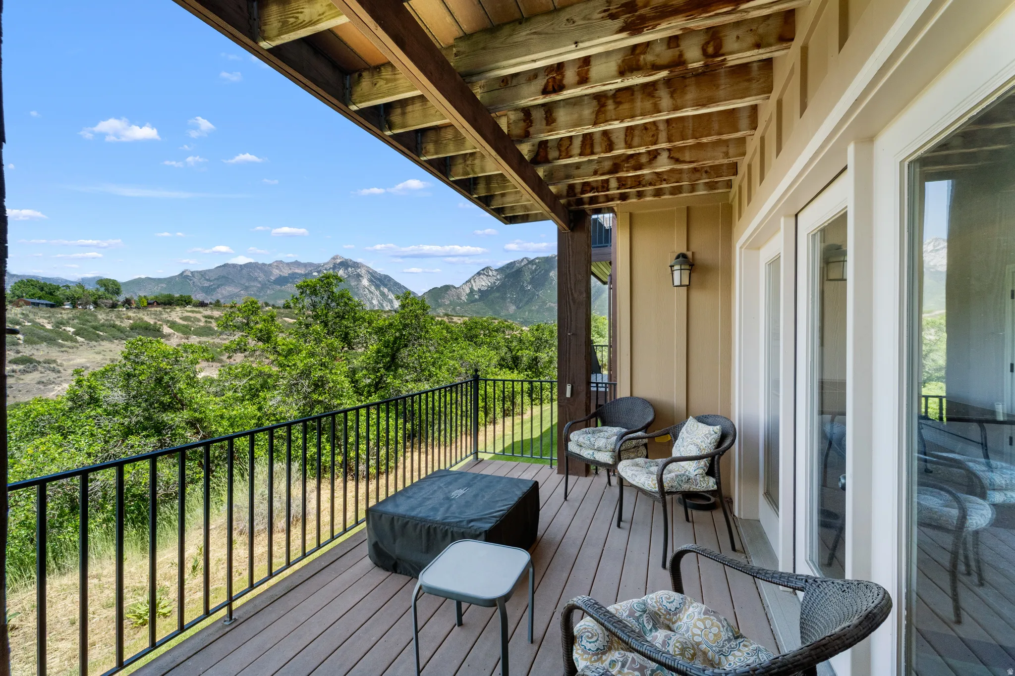 Covered outdoor deck featuring composite decking, black metal railings, and a prominent mountain backdrop
