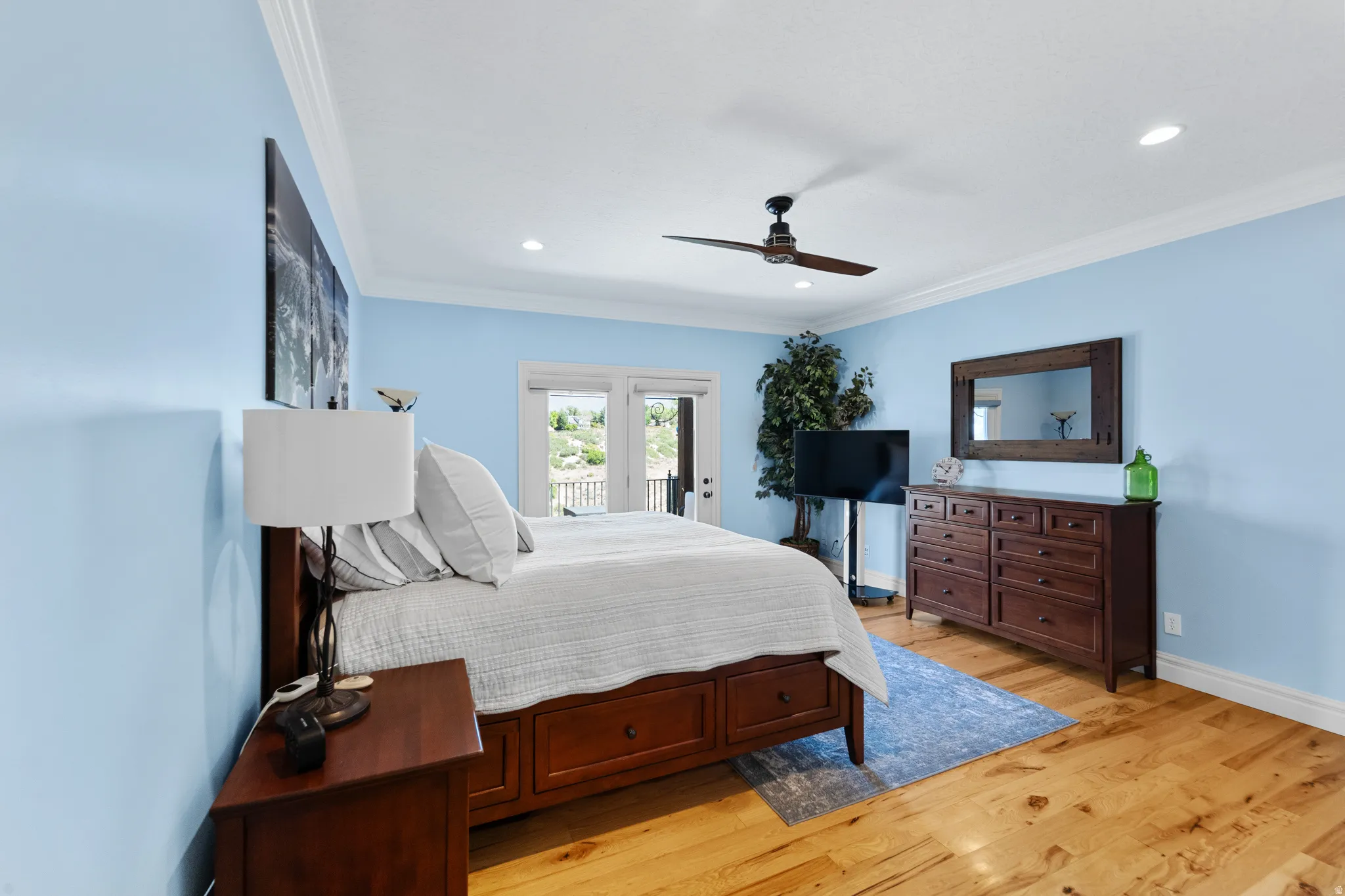 Bedroom featuring wood-finish flooring, light blue walls, and white crown molding
