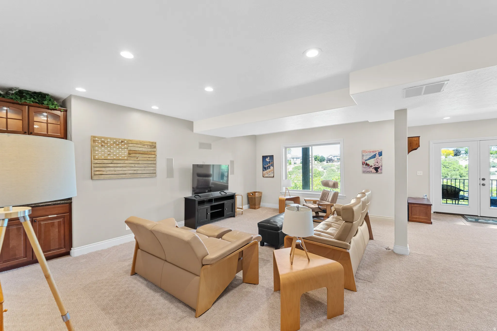 Spacious living area featuring carpet flooring, recessed lighting, and a built-in cabinetry with glass doors