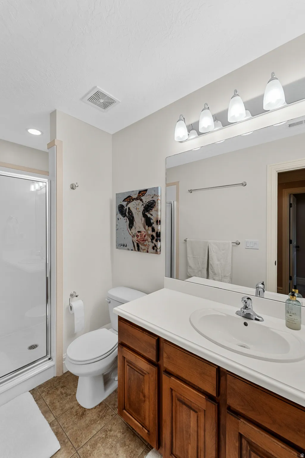 Bathroom featuring a single vanity with wood-finish cabinetry, a white countertop, and an integrated white sink
