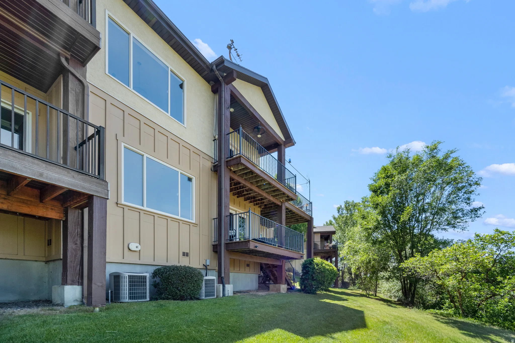 Multi-level structure featuring light stucco siding and dark brown trim
