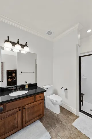 Bathroom featuring a wood-finish vanity with a dark countertop and undermount sink