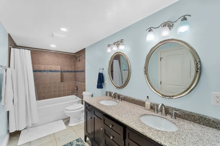 Double vanity featuring granite-look countertops, undermount sinks, and framed oval mirrors