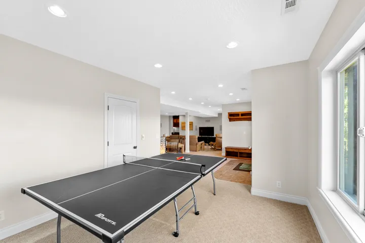 Expansive recreation room featuring recessed lighting, a neutral color palette, and a large window