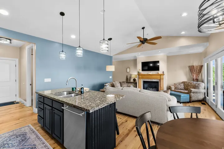 Open concept living space featuring a kitchen island with stone countertop, stainless steel sink, and dishwasher