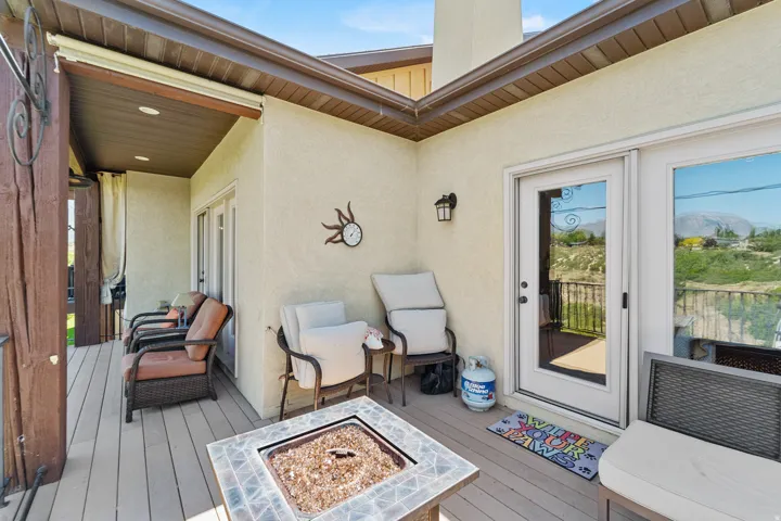 Expansive outdoor deck featuring wood-finish flooring, a built-in fire pit with tile surround, and a covered patio area with recessed lighting