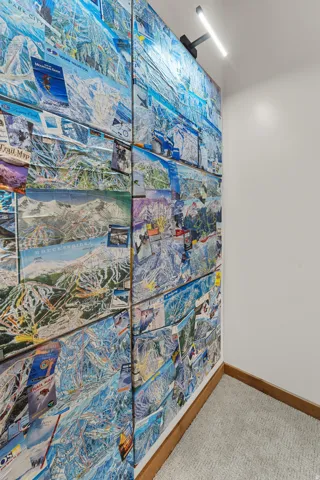 Accent wall featuring a collage of ski trail maps, complemented by a modern linear light fixture