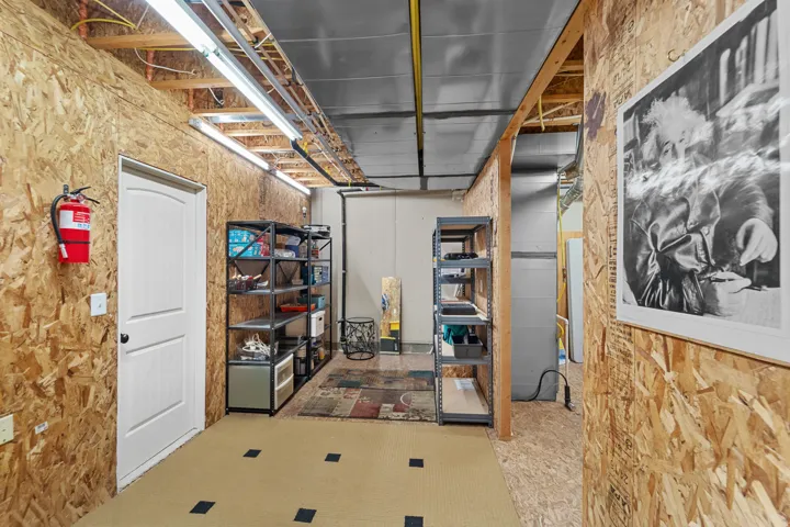 Utility space featuring oriented strand board walls and exposed ceiling joists
