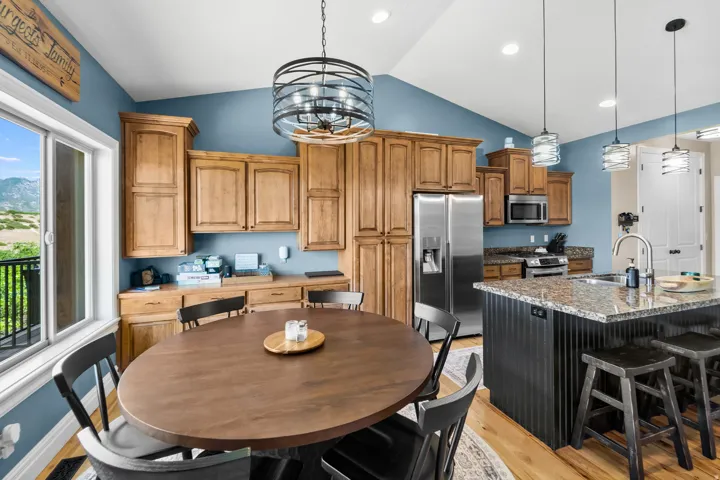 Kitchen featuring wood-finish cabinetry, stainless steel appliances, and a central island with a sink and granite-style countertop