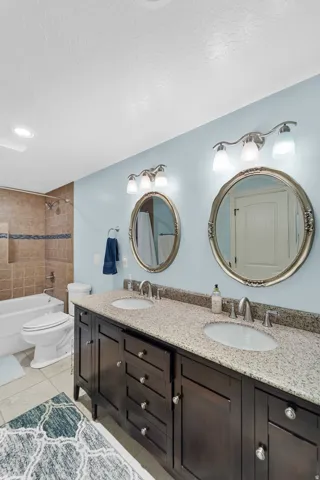 Bathroom with a double vanity featuring a light-colored speckled countertop, two oval undermount sinks, and dark wood-finish cabinetry