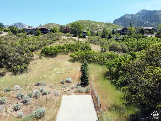 Expansive mountainous terrain with varied green foliage and several properties interspersed