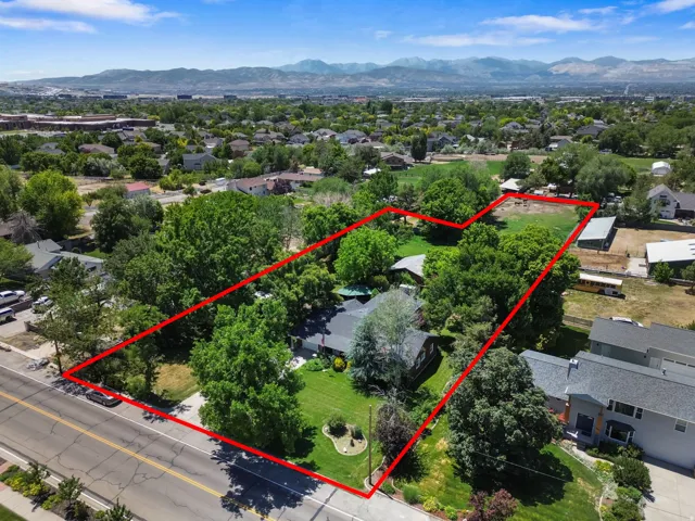Expansive property featuring a large residential lot with mature trees, a substantial grassy area, and a backdrop of distant mountains