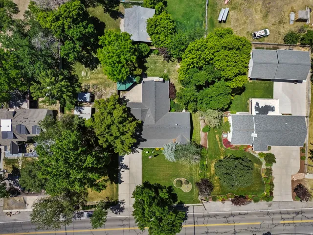 Aerial perspective showcasing the property's expansive lot with mature landscaping, multiple structures, and paved driveways