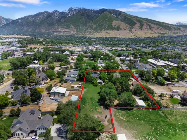Expansive lot with mature trees and significant open space, bordered by residential properties and featuring distant mountain scenery