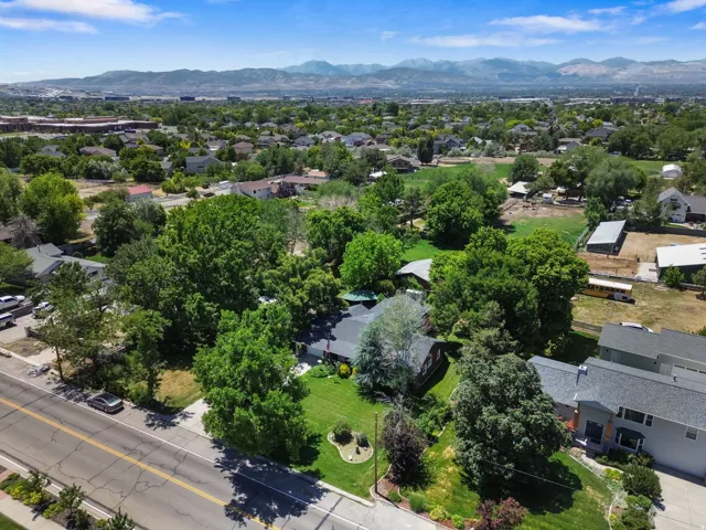 Expansive green lot with established landscaping, mature trees, and a mountain backdrop